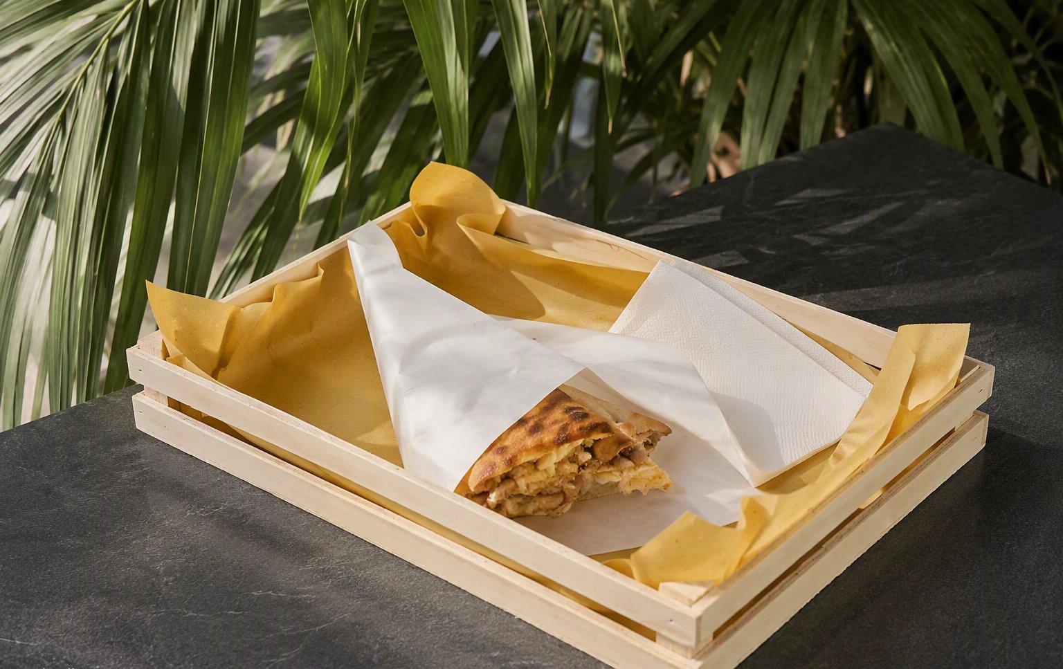 Il vassoio di legno con il panino incartato e le piante